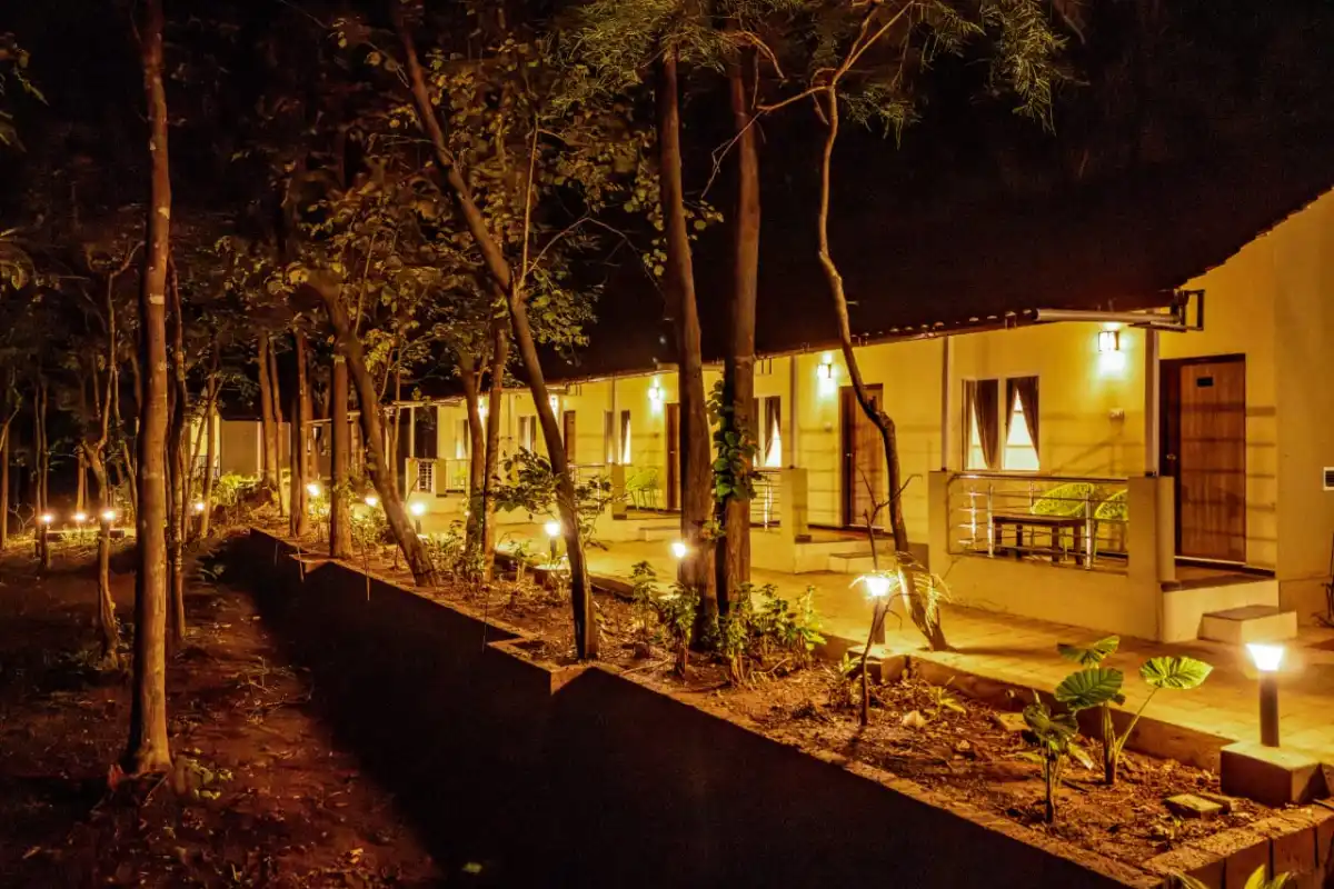 Cottages illuminated at night at Rain Forest Resort Dandeli