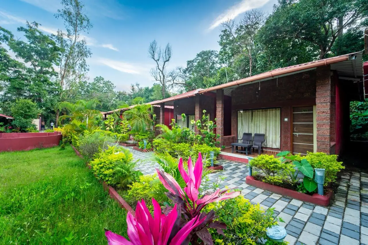 Garden pathway lined with trees and lawns inside Wild Wings Jungle Resort